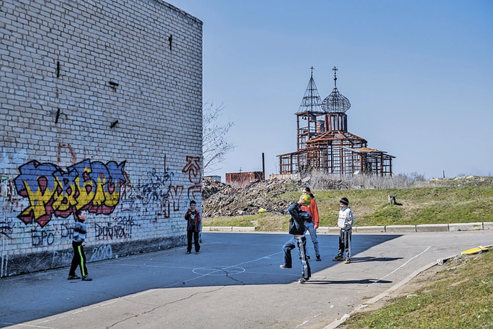Украина, Донецкая область, Красный партизан. Дети играют в мяч на улице рядом со сгоревшей церковью.