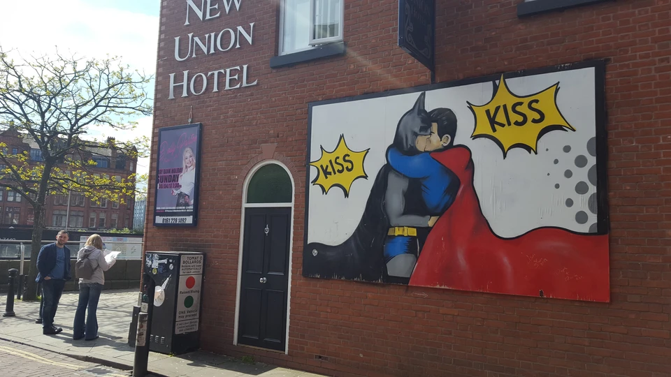 На стенах вызывающие плакаты. Например, целующегося Бэтмена и Супермена.