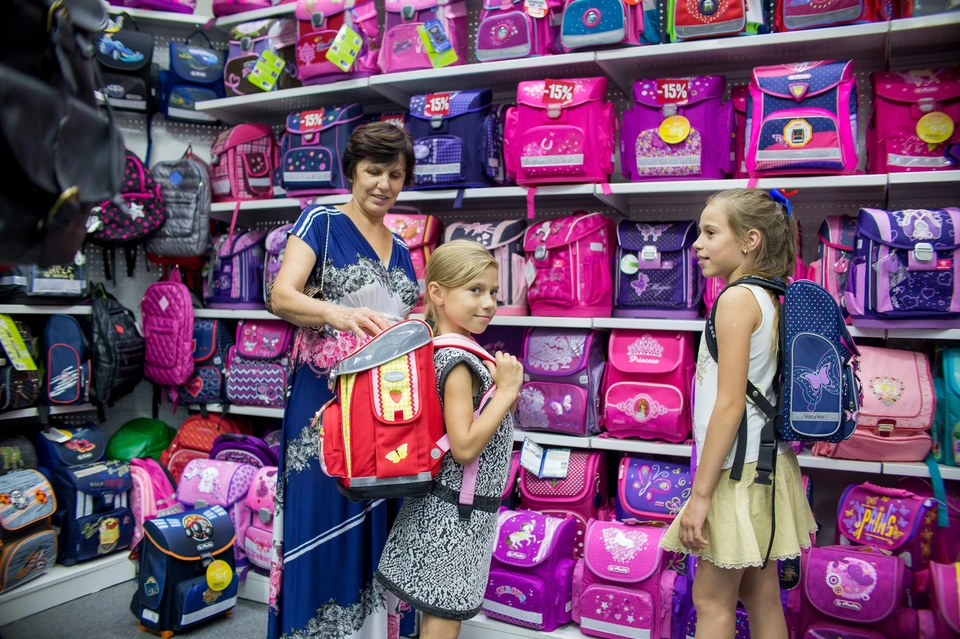 Женщина помогает выбрать рюкзак в отделе школьных товаров