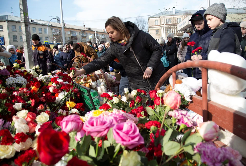Люди несут цветы к зданию сгоревшего ТЦ "Зимняя вишня" в Кемерово
