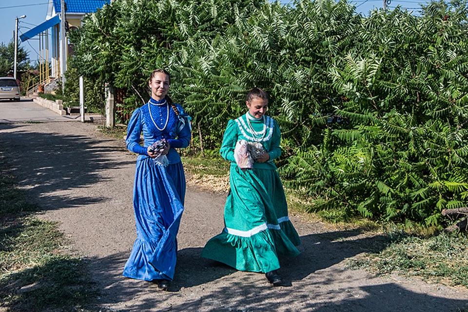Две прекрасные девушки-казачки, в старинных платьях, косы – с руку толщиной, расхаживают лебедками