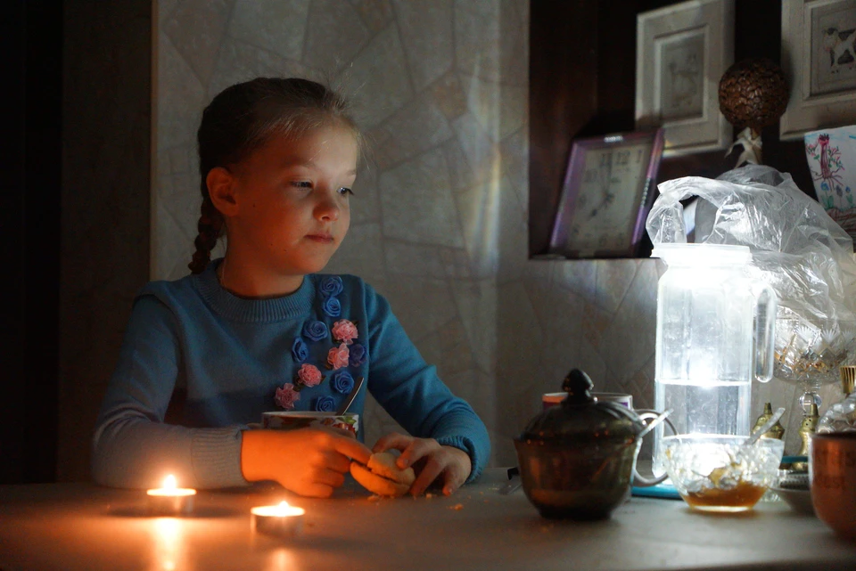 Девочка завтракает при свечах из-за отключения электроэнергии