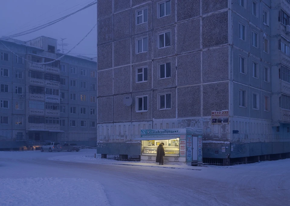 Женщина покупает продукты в киоске во дворе дома в Якутске. Фундамент зданий здесь возводится на сваях, чтобы тепло от домов не подтапливало вечную мерзлоту. Фото: Алексей Васильев.