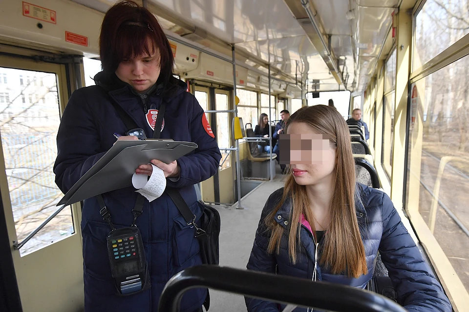 Контролер выписывает штраф за безбилетный проезд в московском трамвае.