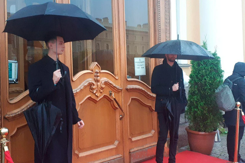 Перед Юсуповским дворцом гостей торжества в честь свадьбы Бондарчука и Андреевой встречают мужчины с черными зонтами - в Петербурге дождь.