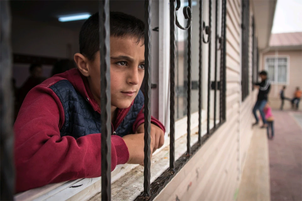 Сирийский подросток выглядывает из окна лагеря беженцев, Турция.