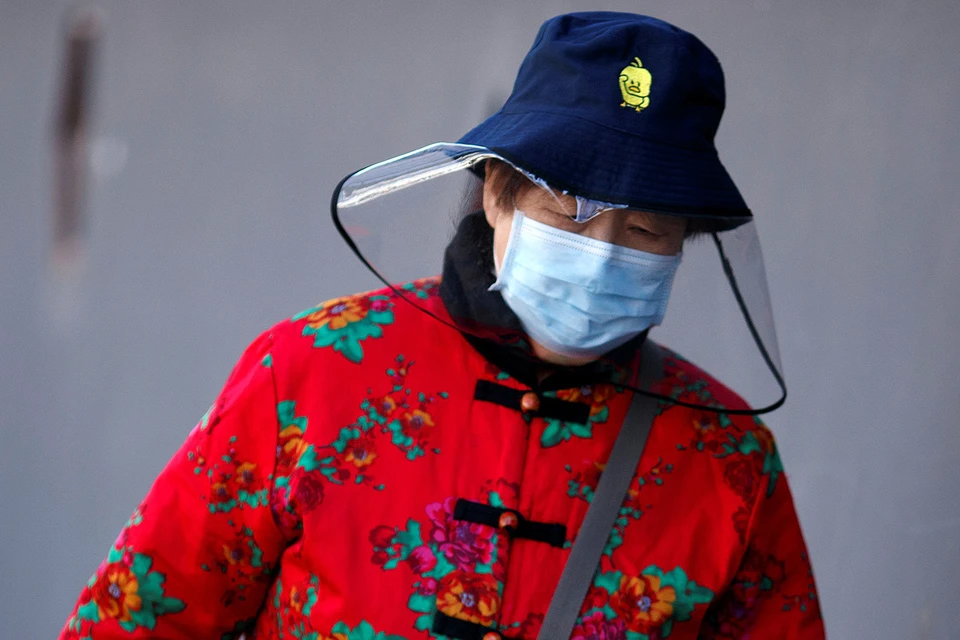 Жительница Пекина идет по улицам города в маске против коронавируса.