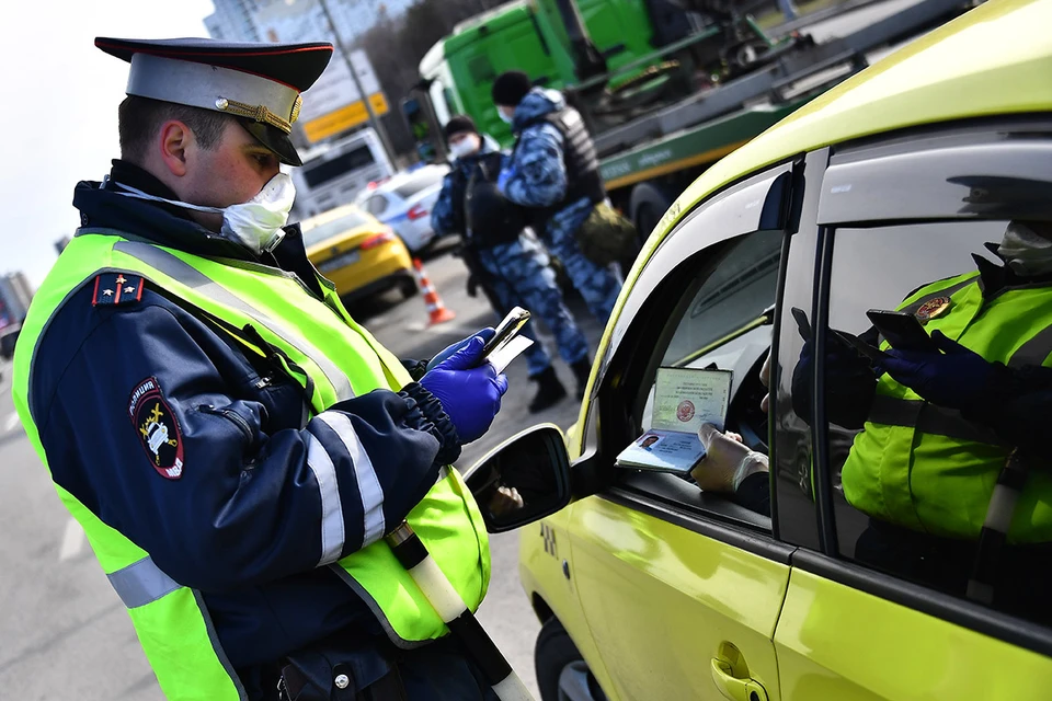 Сотрудник дорожно-патрульной службы ГИБДД во время проверки электронного пропуска у водителя на блокпосту при въезде в Москву.
