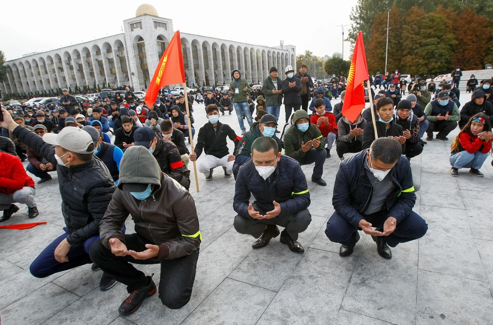 Участники митинга молятся на площади в центре Бишкека.