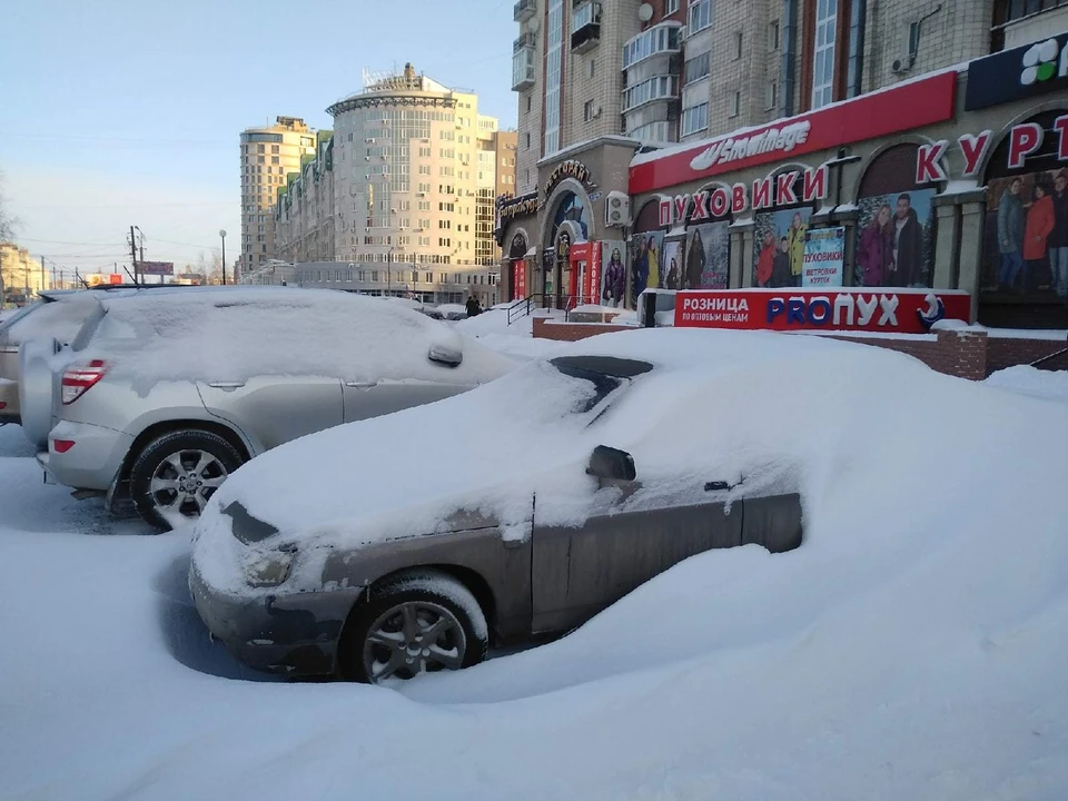 Некоторые машины на парковке накрыло огромным слоем снега.