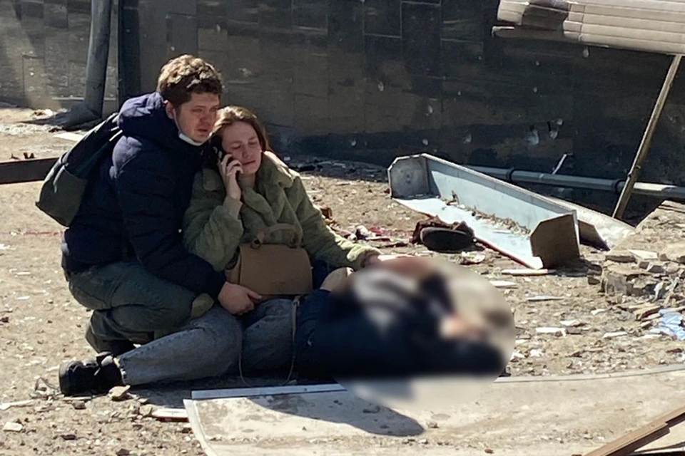 Девушка обнимает мертвую мать, рядом с ней на коленях стоит муж или парень, просто прижимается к ней, голова к голове.