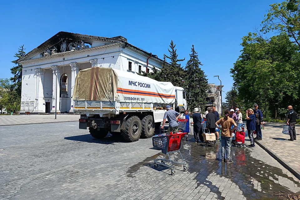 Cerca del teatro Mariupol incendiado hay un automóvil del Ministerio de Situaciones de Emergencia con agua potable.