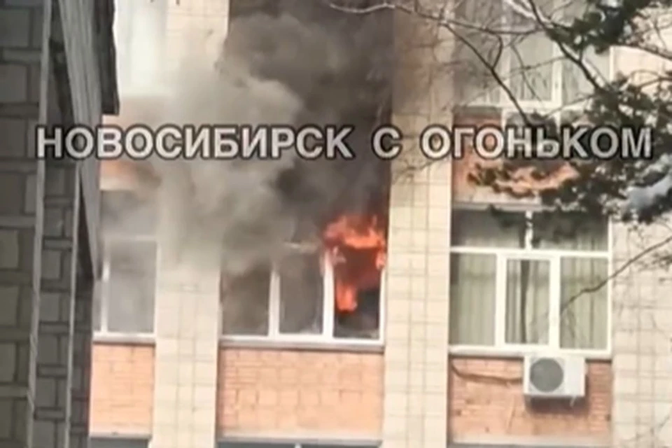 Из окна колледжа вырываются языки пламени и валит темный дым. Фото: стоп-кадр из видео / Новосибирск с огоньком
