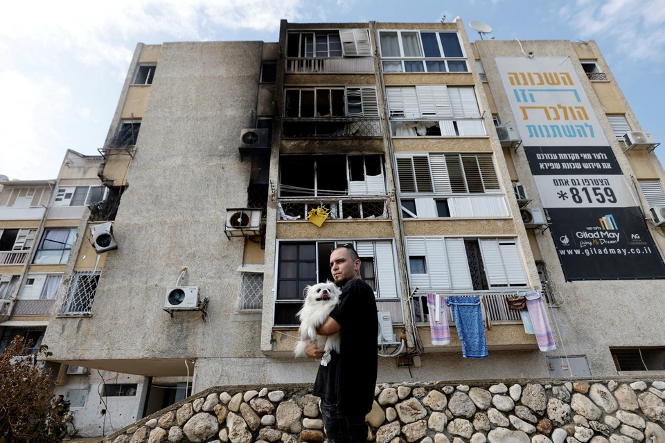 Житель израильского города Ашкелон у дома, пораженного палестинской ракетой.