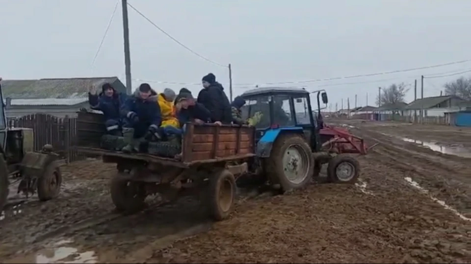 В соцсетях распространилось видео, в котором показано, как на телеге, прикрепленной к трактору, местных детей везут к знаниям по раскисшей поселковой дороге.