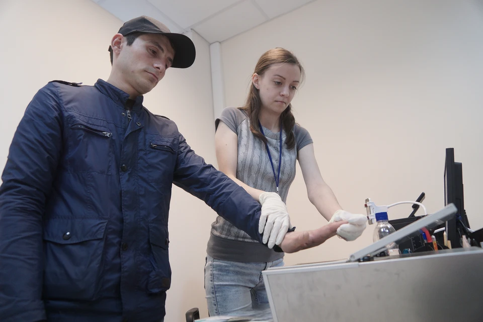 Екатеринбург. Сотрудница миграционного центра проводит дактилоскопию иностранного гражданина во время оформления документов.