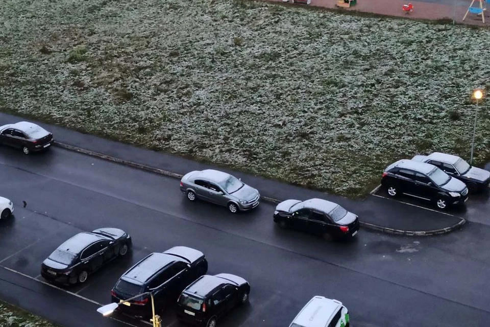 Снежинки припорошили машины и траву у дома.