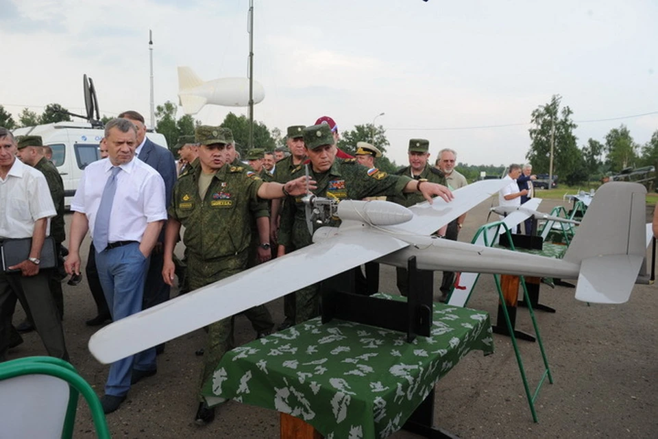 Министр обороны России Сергей Шойгу и сопровождающие его лица осмтаривают мобильное средство радиационной разведки на беазе бепилотного летательного аппрата.