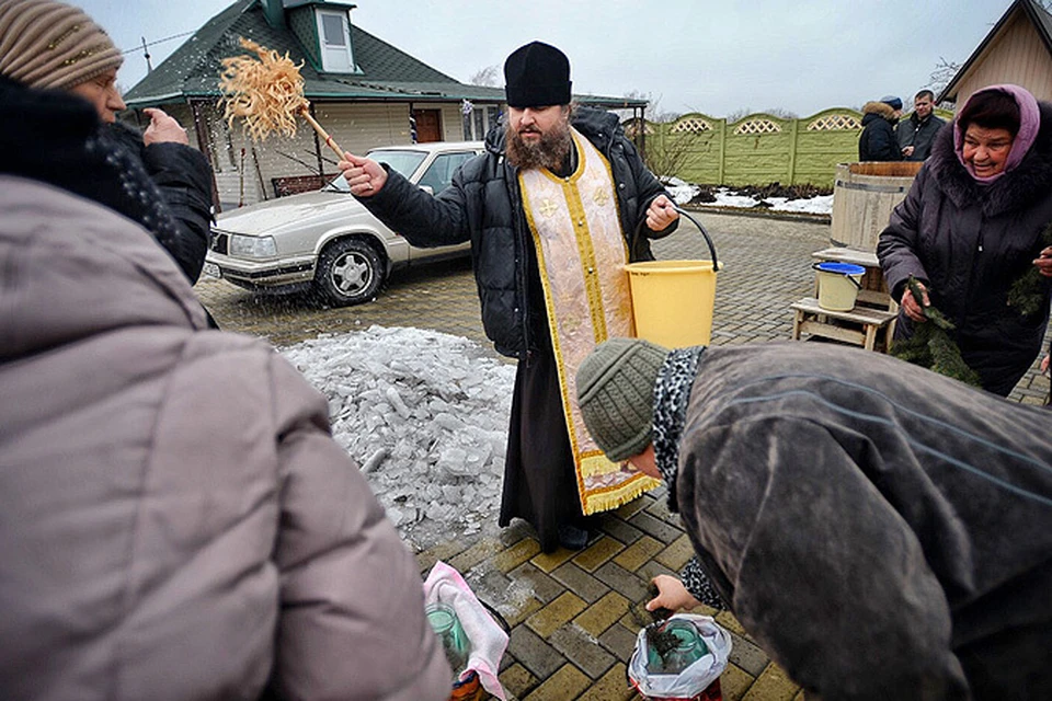 Отец Владимир окропляет прихожан святой водой накануне празднования Крещения Господнего в Александровке, Донецкой области, которая находится на линии соприкосновения между ДНР и территорией контролируемой нацгвардией Украины.